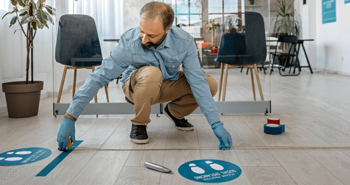 Man applying social distancing stickers to floor
