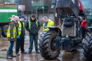 three workers being trained to use a tractor safely 
