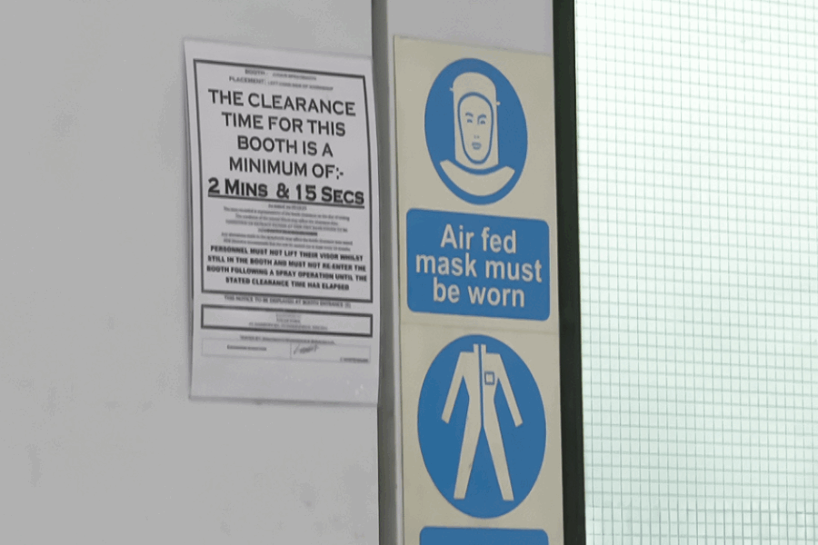 Signage on the entrance of a spray booth showing mist clearance times and that air-fed masks must be worn