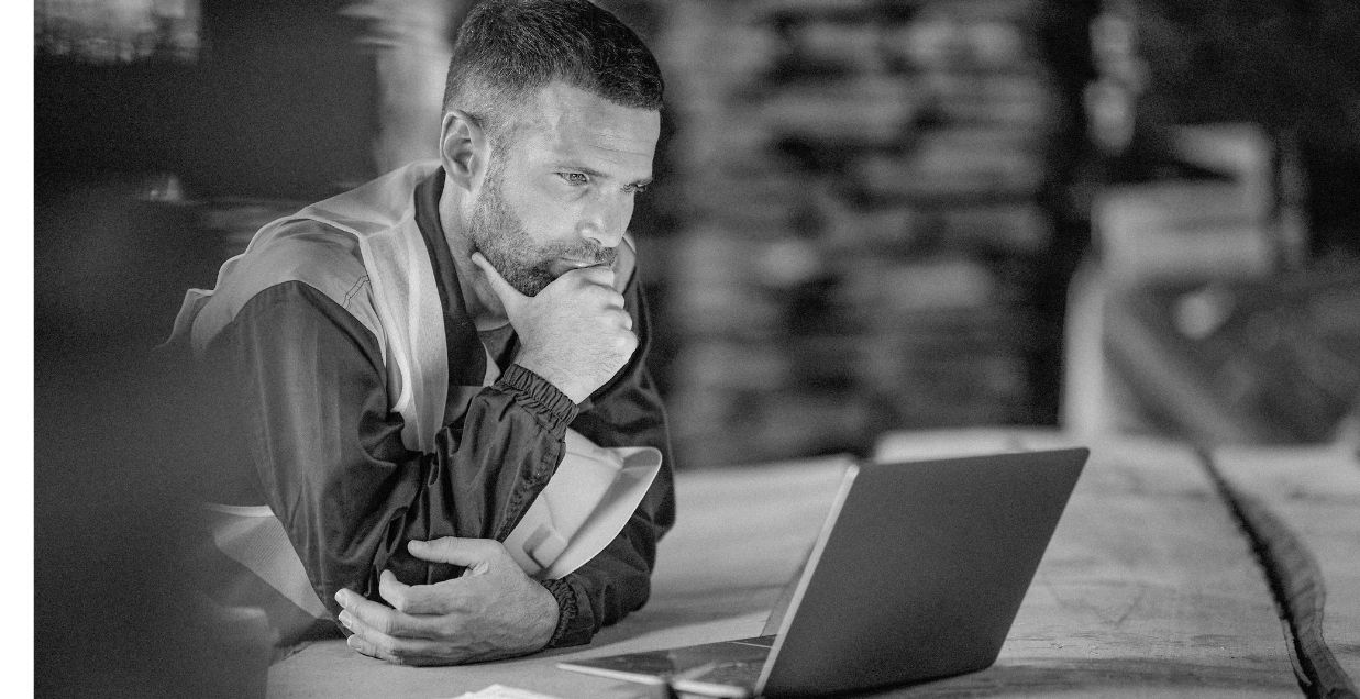 Stone worker sat at work table looking at a laptop screen
