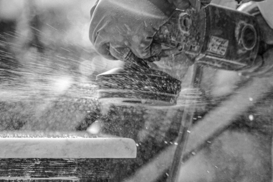 Close up of angle grinder with polishing attachment and water suppression on a block of marble worktop