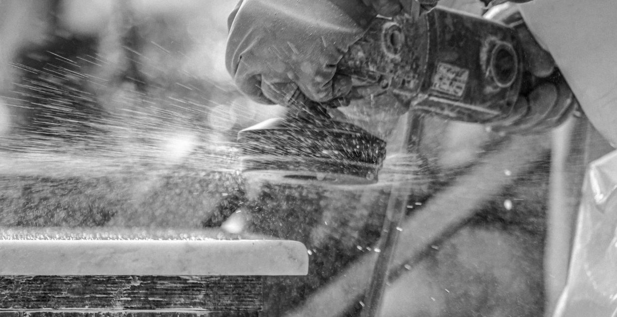 Close up of angle grinder with polishing attachment and water suppression on a block of marble worktop